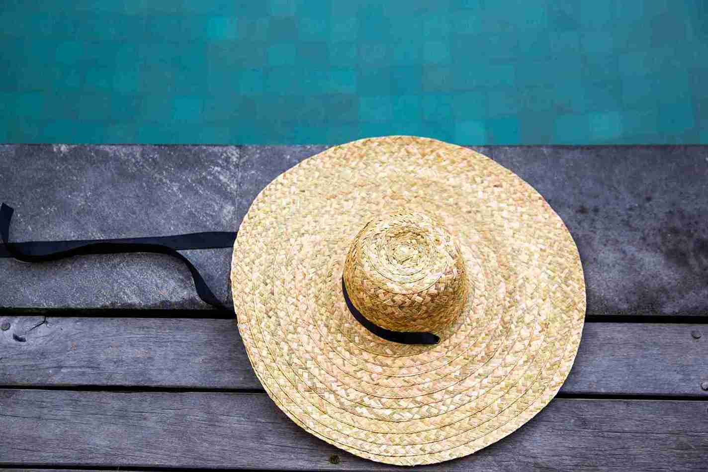 Woven straw hat placed by the poolside – symbolic image for the question “Can You Wear a Hat After Hair Transplant.