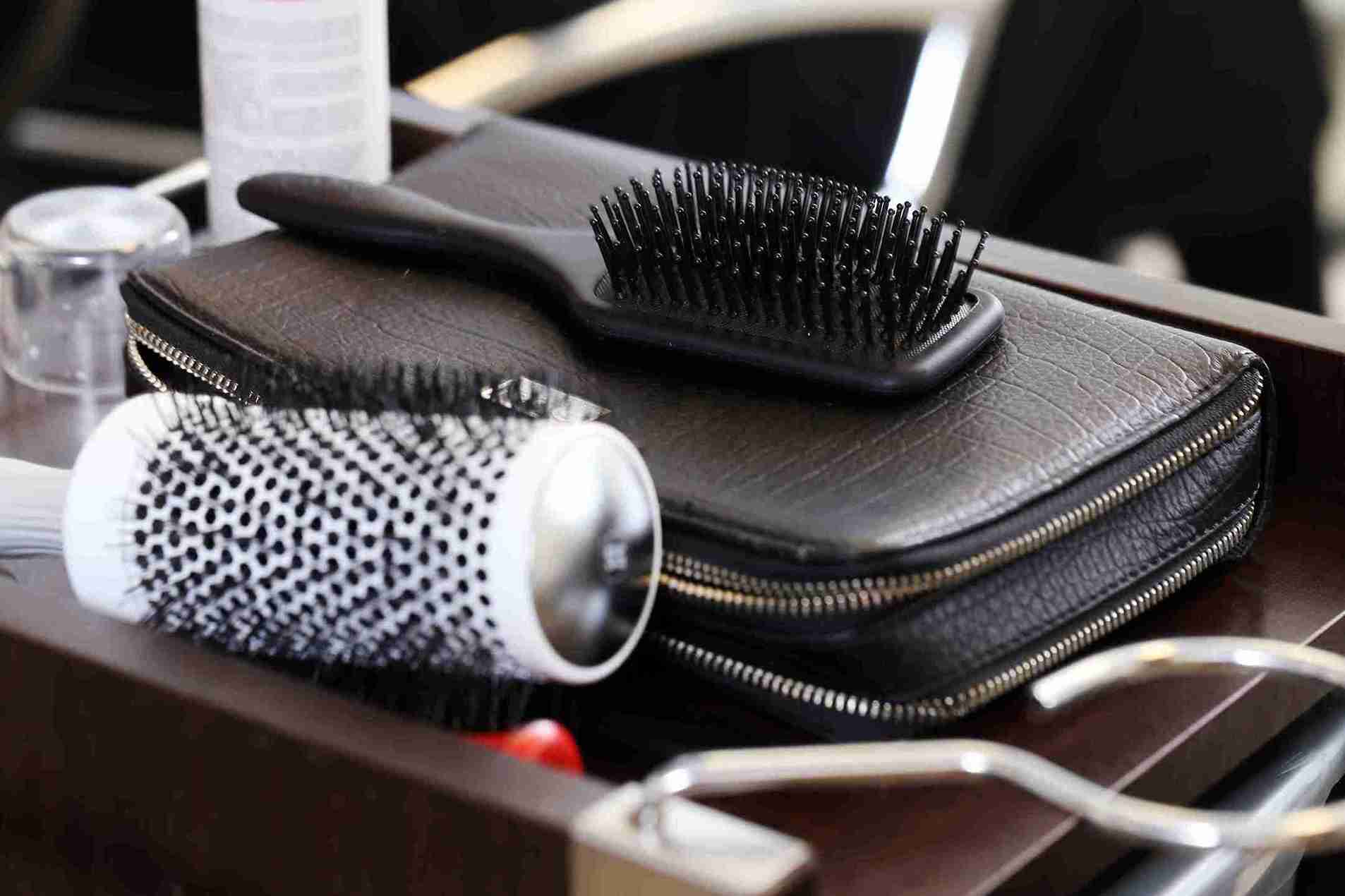 Cepillos de cabello sobre una mesa de salón, herramientas esenciales para cuidar y estimular el crecimiento del cabello de forma saludable.