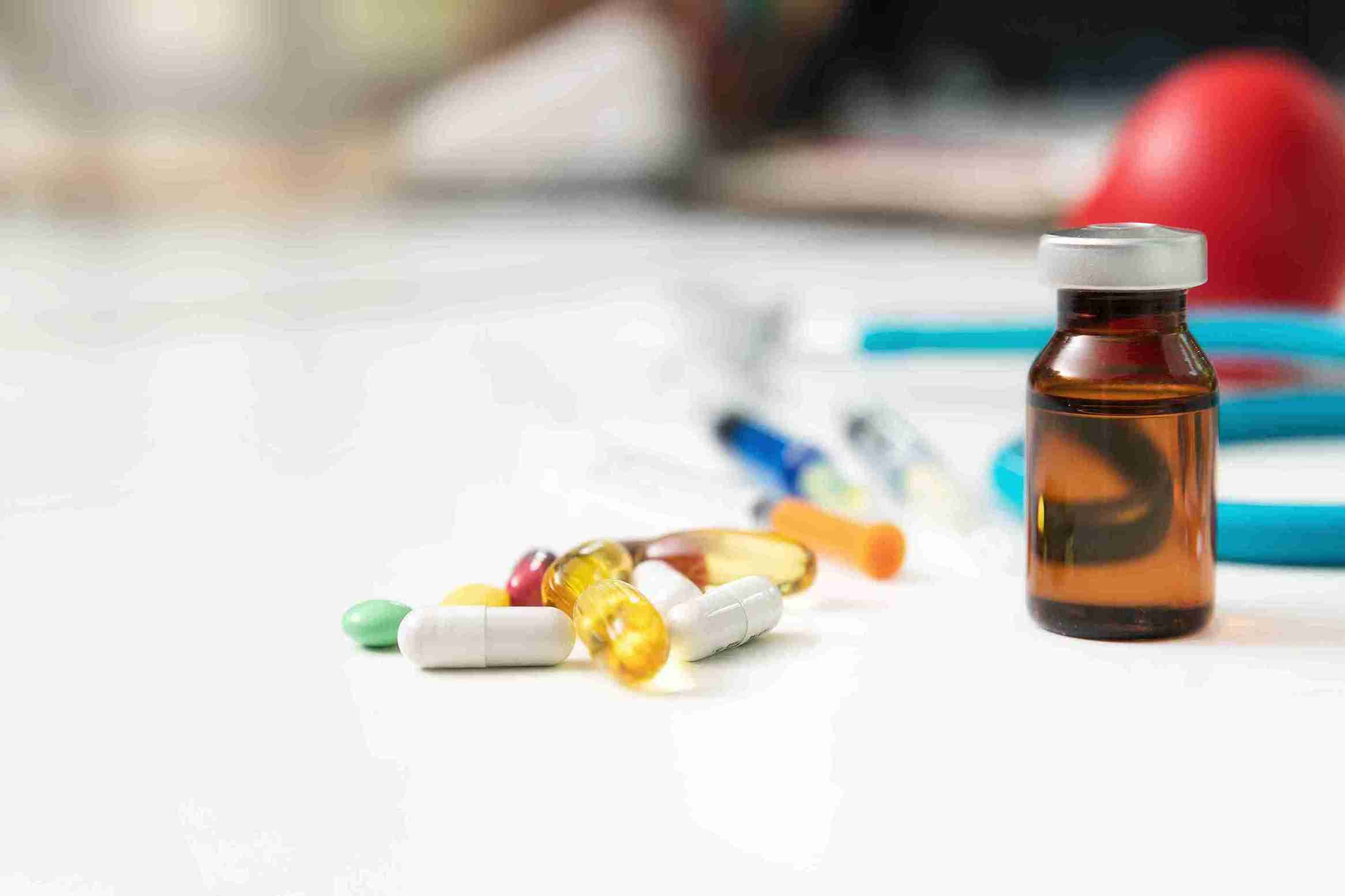 Verschiedene Tabletten gegen Haarausfall neben einer Medizinflasche und medizinischem Zubehör auf einem weißen Tisch