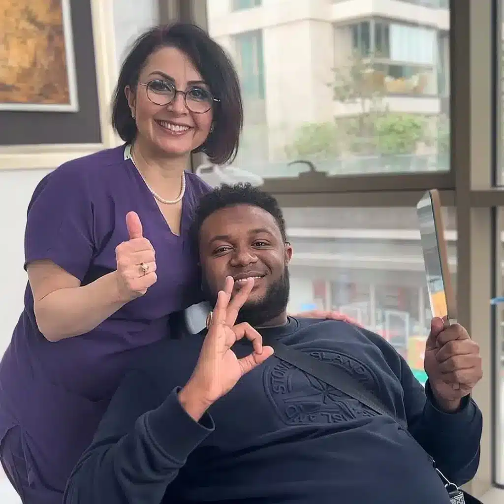 Patient beim Zahnbleaching in einer modernen Zahnklinik in der Türkei, lächelt zufrieden und zeigt Daumen hoch neben der Zahnärztin – Bleaching Türkei.