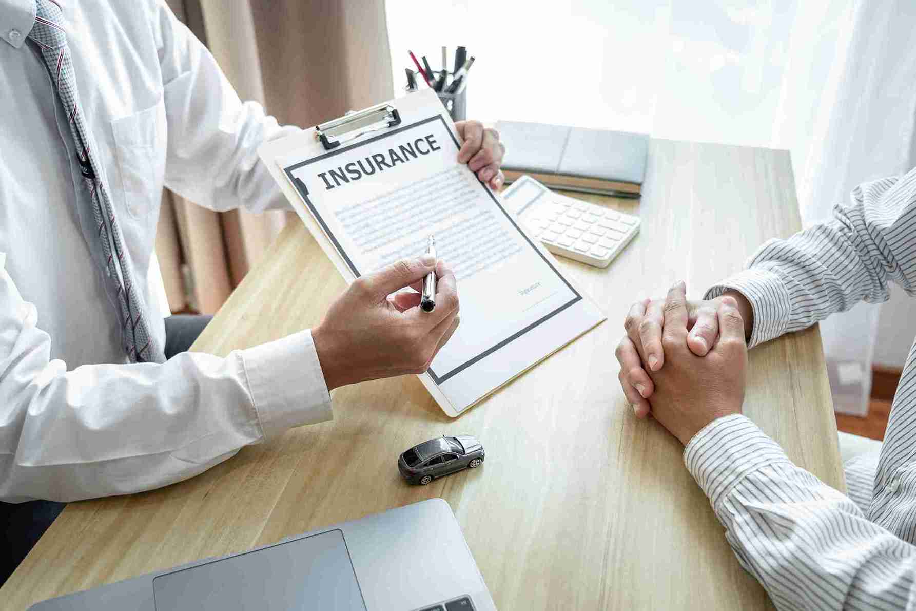 A doctor discussing an insurance policy with a patient at a desk, illustrating the topic “Does Insurance Cover Rhinoplasty” and medical coverage consultation.