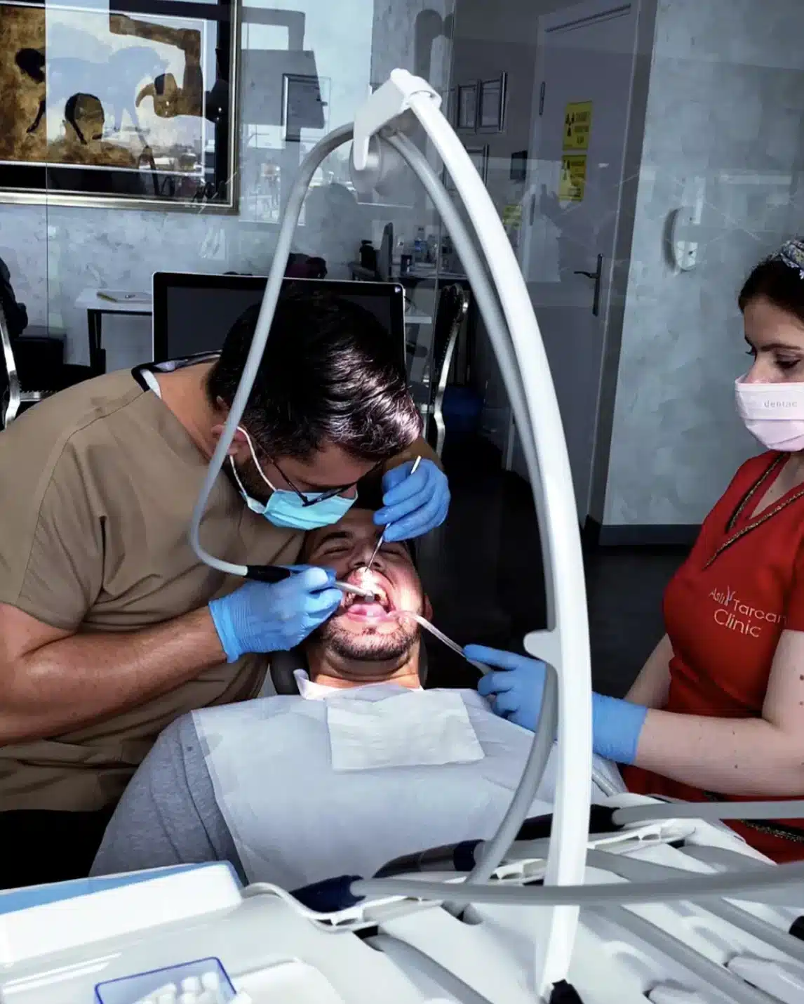 Zahnärztliche Behandlung in moderner Klinik: Zahnarzt und Assistenz behandeln einen Patienten während der Vorbereitung auf ein Hollywood Smile mit professioneller Zahnästhetik.