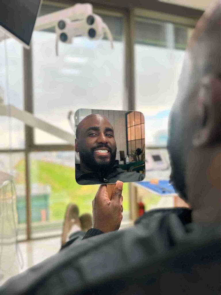 Zufriedener Patient betrachtet sein strahlendes Lächeln im Spiegel nach einer erfolgreichen Zahnbehandlung Türkei in einer modernen Zahnarztpraxis.