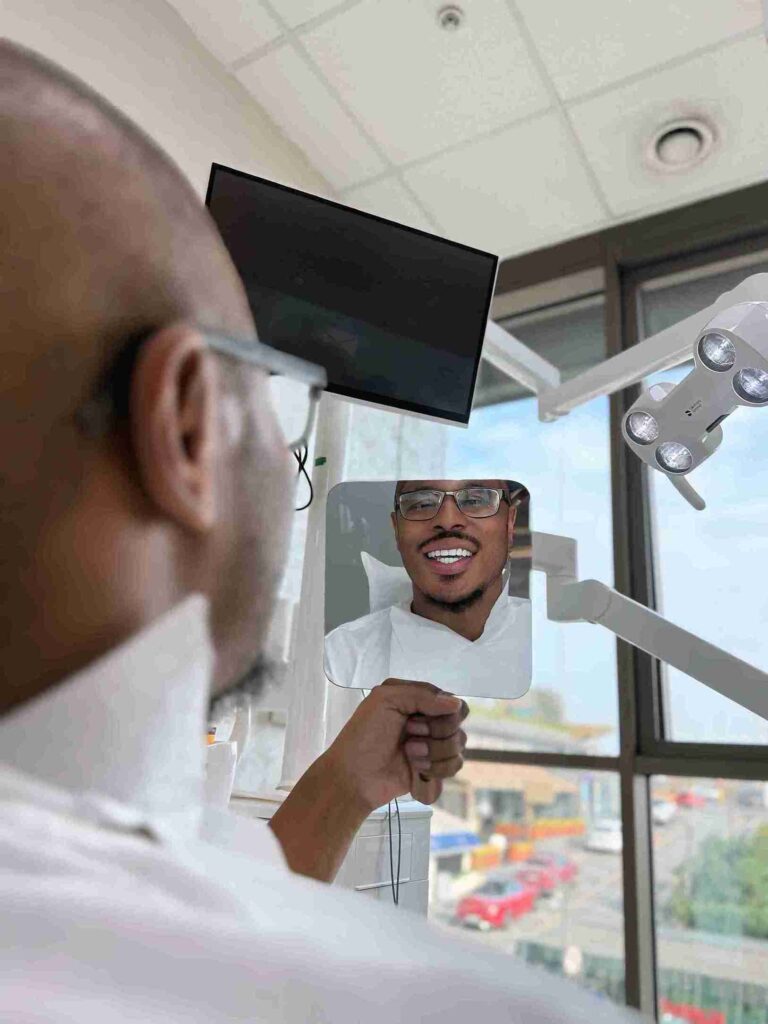Patient betrachtet sein neues Lächeln im Spiegel nach einer erfolgreichen Zahnbehandlung Türkei in einer modernen Zahnklinik mit professioneller Ausstattung.