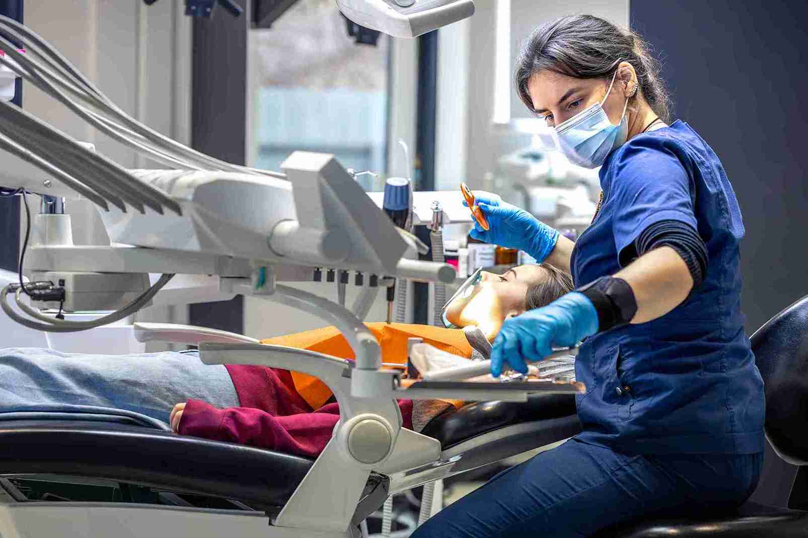 Zahnärztin behandelt Patientin in moderner Zahnarztpraxis während einer Zahnbehandlung im Ausland mit professioneller Ausrüstung und medizinischen Instrumenten.