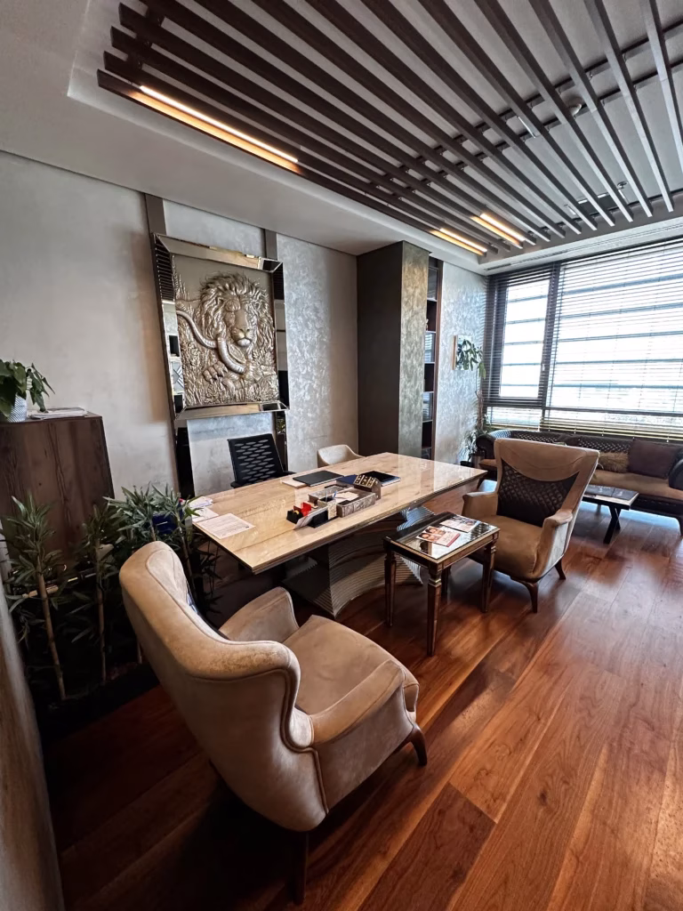 “Elegante oficina de clínica estética con mobiliario de lujo, mesa de mármol, sillones acolchados y detalles decorativos, representando un entorno premium para servicios de Trasplante Capilar Turquía.